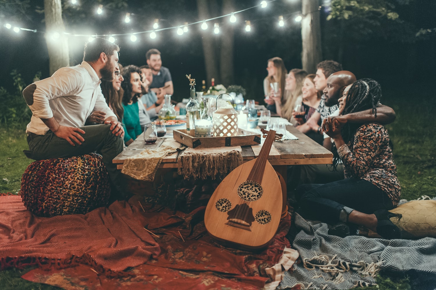 Sommerliche Abendgesellschaft mit Lichterketten an einer langen Tafel